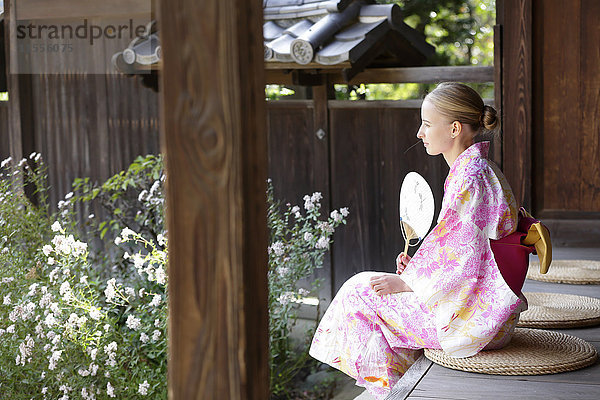 Weiße Frau trägt Yukata in einem traditionellen japanischen Haus