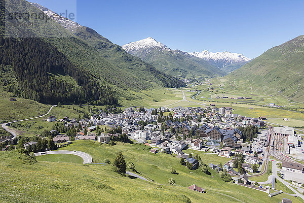 Das Alpendorf Andermatt  umgeben von grünen Wiesen und verschneiten Gipfeln im Hintergrund  Kanton Uri  Schweiz  Europa