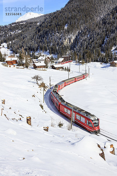 Roter Zug der Rhätischen Bahn fährt in der verschneiten Landschaft von Arosa  Bezirk Plessur  Kanton Graubünden  Schweiz  Europa