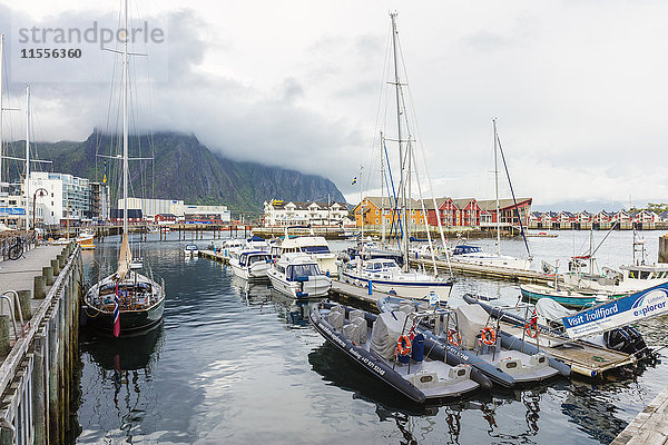 Wolken auf felsigen Gipfeln umrahmen die Boote im Hafen des Fischerdorfs Svolvaer  Vagan  Lofoten  Norwegen  Skandinavien  Europa