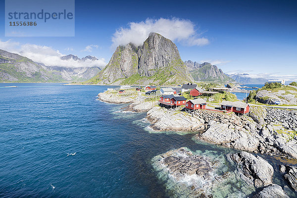 Blick von oben auf das Fischerdorf  eingerahmt von blauem Meer und hohen Gipfeln Hamnoy  Moskenesoya  Bezirk Nordland  Lofoten  Norwegen  Skandinavien  Europa