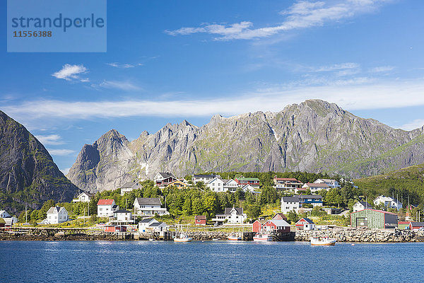 Das blaue Meer umrahmt das Fischerdorf und die felsigen Gipfel  Reine  Moskenesoya  Lofoten  Norwegen  Skandinavien  Europa