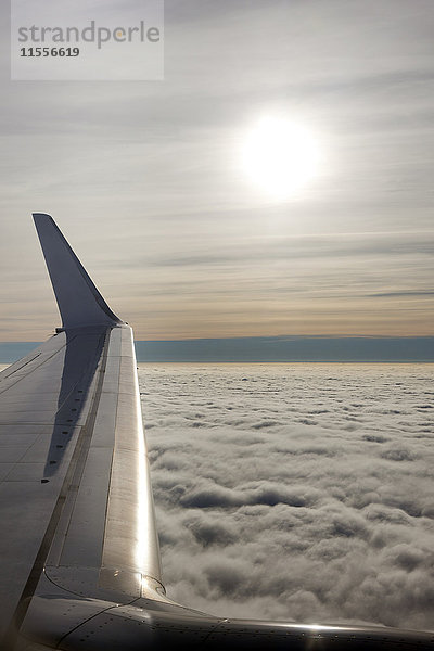 Flugzeugflügel mit tiefliegenden Wolken und Sonnenaufgang  Vereinigtes Königreich  Europa