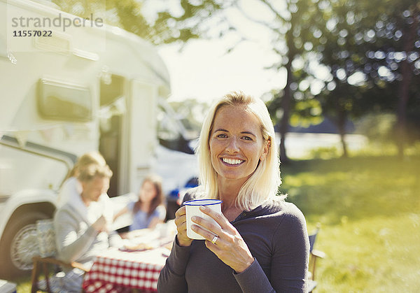 Portrait lächelnde Frau trinkt Kaffee draußen im sonnigen Wohnmobil