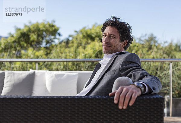 Porträt selbstbewusster Geschäftsmann auf Balkon-Terrassen-Sofa
