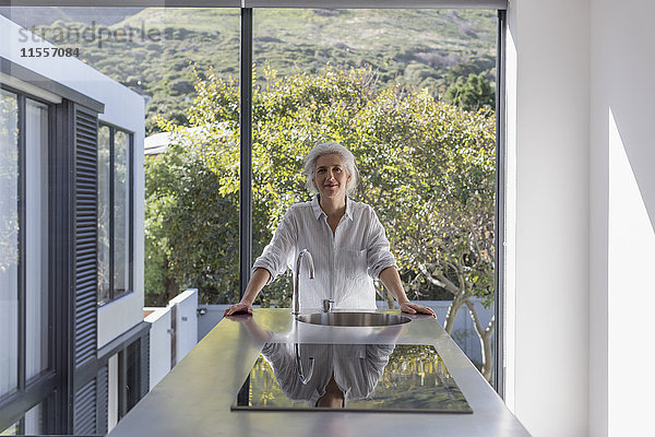 Porträt zuversichtlich  reife Frau steht in der modernen Heimat Schaufenster Interieur Küche