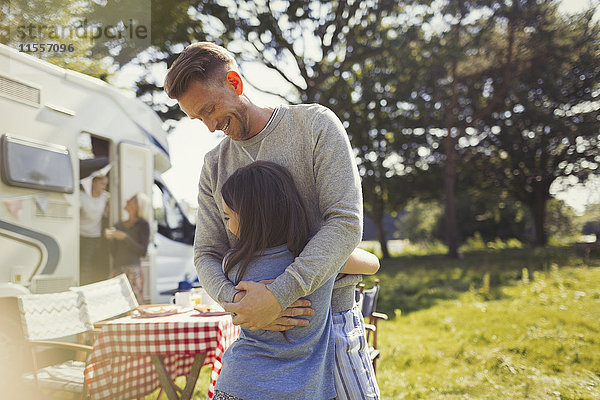 Lächelnder Vater umarmt Tochter draußen sonniges Wohnmobil