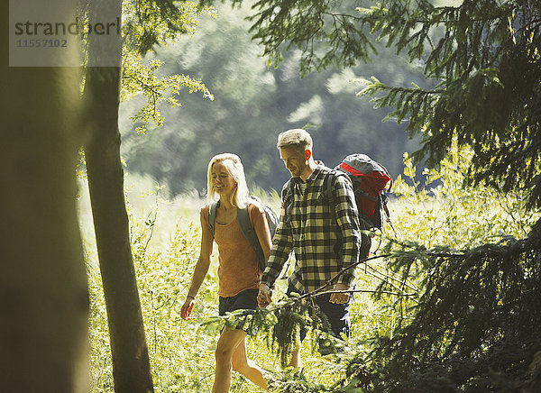 Paar mit Rucksäcken beim Wandern in sonnigen Wäldern