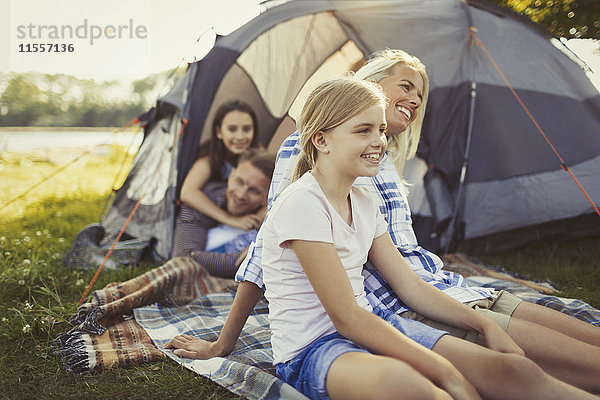 Lächelnde Familie entspannt vor dem Campingplatz-Zelt