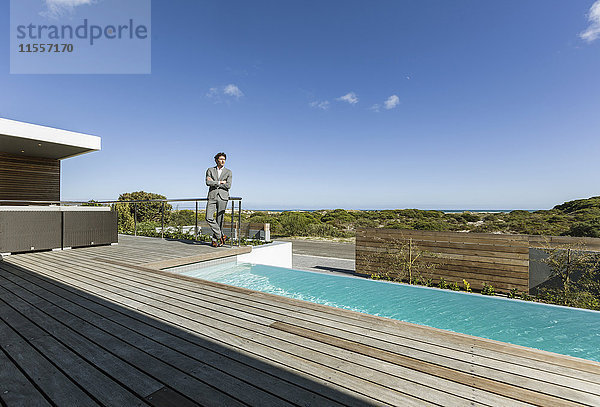 Geschäftsmann auf sonniger  moderner  luxuriöser Terrasse mit Infinity-Pool