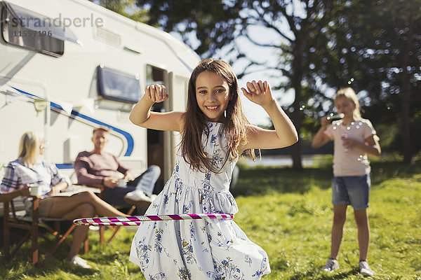 Portrait lächelndes Mädchen  das sich im Plastikband vor dem sonnigen Wohnmobil dreht