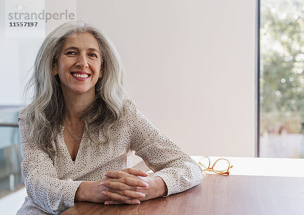 Porträt einer lächelnden  selbstbewussten reifen Geschäftsfrau  die am Tisch sitzt