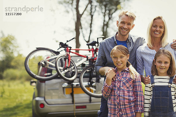 Portrait lächelnde Familie in der Nähe des Autos mit Mountainbikes