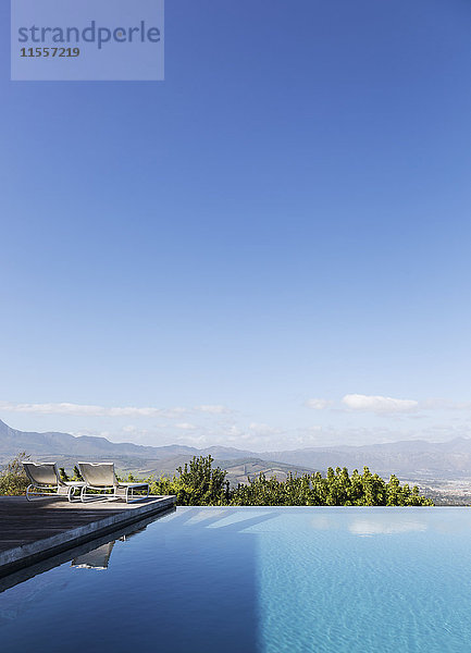 Ruhiger  luxuriöser Infinity-Pool mit Blick auf die Berge unter sonnigem  blauem Himmel