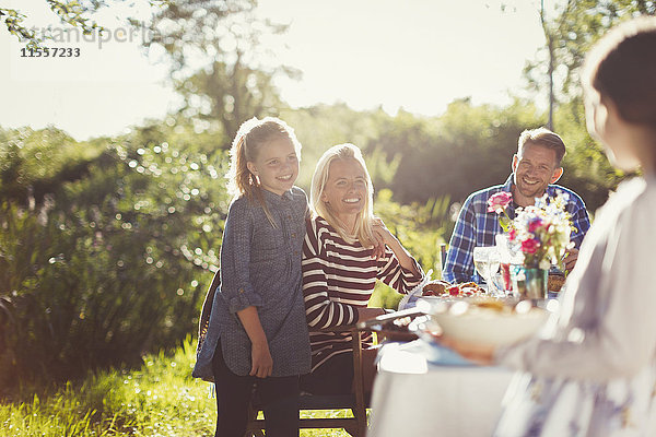 Glückliche Familie beim Mittagessen am sonnigen Gartenparty-Tisch