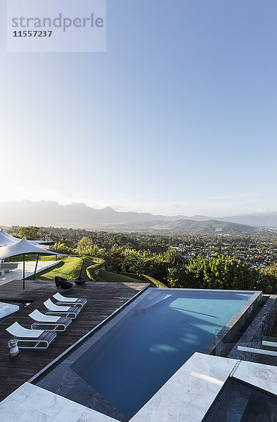 Home Schaufenster Außen Infinity-Pool und Terrasse mit Blick auf die Berge unter sonnigen blauen Himmel