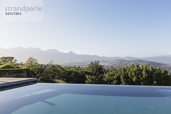 Ruhiger  luxuriöser Infinity-Pool mit Blick auf die Berge unter sonnigem  blauem Himmel