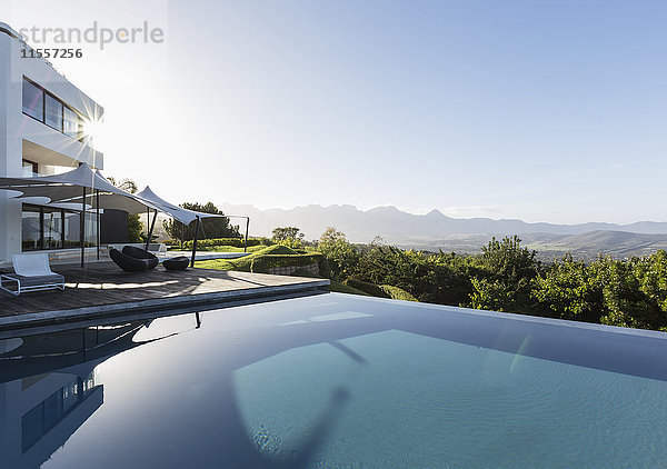 Ruhig  sonnig Haus Schaufenster Außenbereich mit Infinity-Pool und Blick auf die Berge unter blauem Himmel