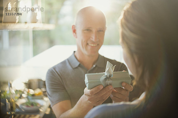 Lächelnder Ehemann schenkt seiner Frau ein Geschenk
