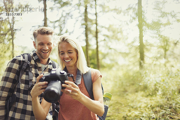 Lächelndes Paar beim Wandern  Betrachten der digitalen Spiegelreflexkamera im Wald