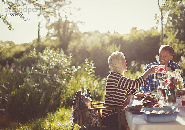 Paar Toasting Weingläser am sonnigen Gartenparty-Terrassentisch