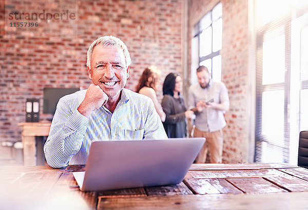 Portrait lächelnder Geschäftsmann bei der Arbeit am Laptop