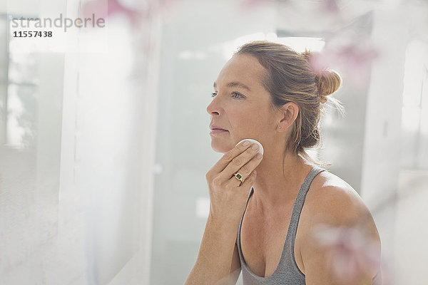 Ältere Frau trägt Make-up im Badezimmerspiegel auf