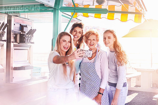 Junge Frauen  die Selfie mit älteren Geschäftsinhabern außerhalb des sonnigen Speisewagens nehmen.
