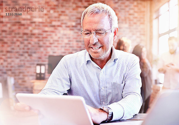 Lächelnder Geschäftsmann mit digitalem Tablett im Büro
