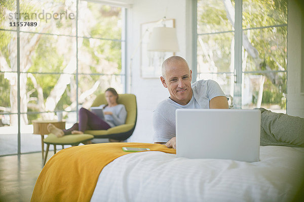Älteres Paar entspannt sich  benutzt Laptop und Tablet im Schlafzimmer