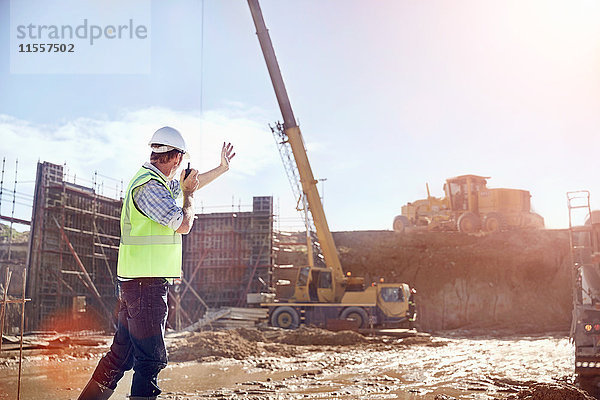 Bauleiter mit Walkie-Talkie-Lenkkran auf sonniger Baustelle