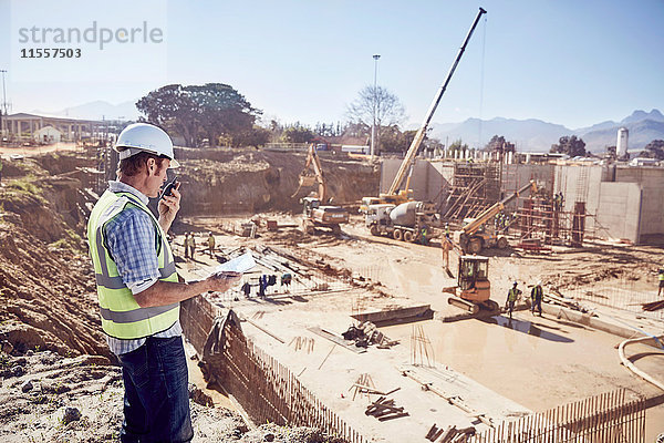 Bauleiter mit Walkie-Talkie auf der sonnigen Baustelle