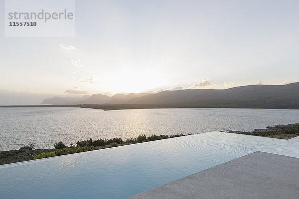 Ruhiger Sonnenuntergang über dem Infinity-Pool und dem Meer