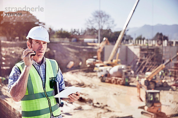 Bauarbeiter-Vorarbeiter im Gespräch über Walkie-Talkie auf der sonnigen Baustelle