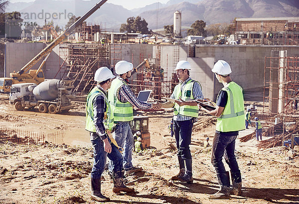 Bauarbeiter und Ingenieure beim Händeschütteln  Treffen auf der sonnigen Baustelle