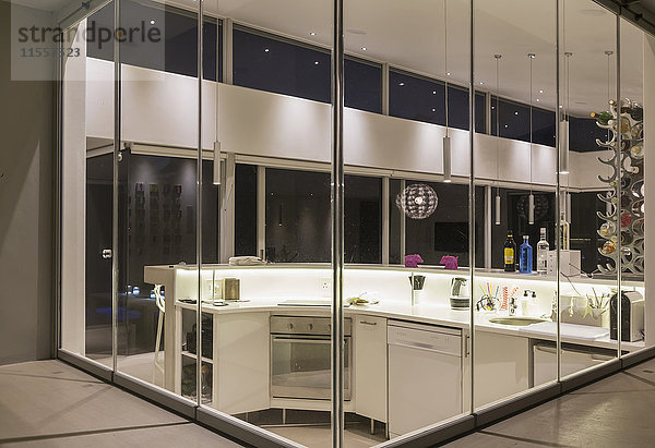 Beleuchtete moderne Luxuswohnung mit Vitrine in der Küche bei Nacht