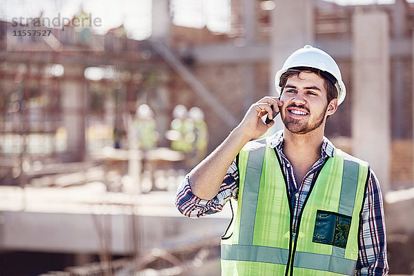 Bauarbeiter beim Telefonieren auf der sonnigen Baustelle
