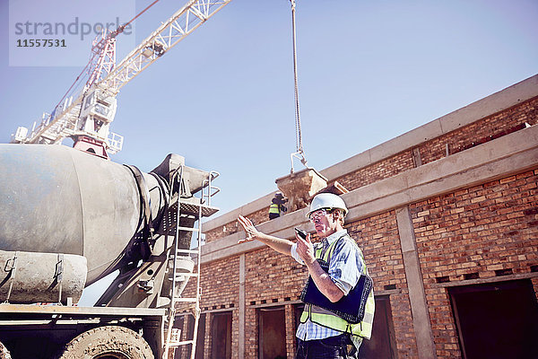 Bauleiter mit Walkie-Talkie auf der sonnigen Baustelle