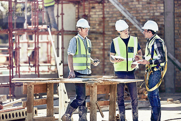 Bauarbeiter und Vorarbeiter im Gespräch auf der sonnigen Baustelle