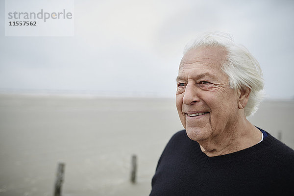 Lächelnder älterer Mann schaut weg am Strand