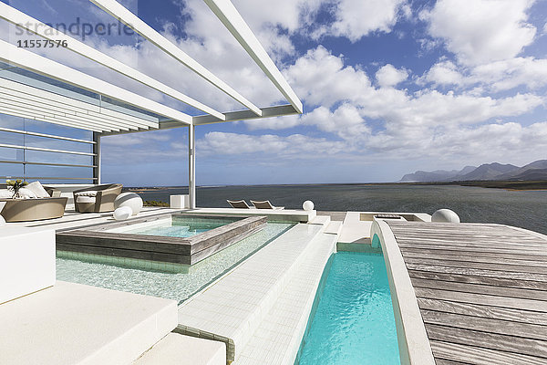Sonnige  ruhige  moderne Luxus-Terrasse mit Swimmingpool und Steg mit Meerblick