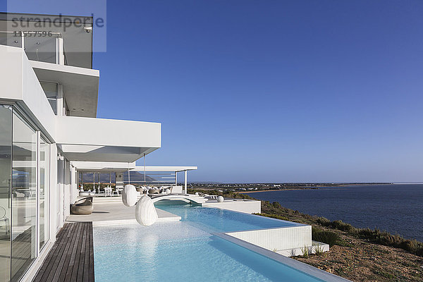 Sonniges  ruhiges  modernes  luxuriöses Haus mit Pool und Meerblick unter blauem Himmel.