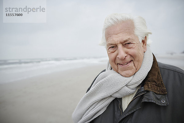 Porträt souveräner Senior mit Schal am Winterstrand