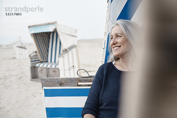 Lächelnde Seniorin schaut weg am Strand