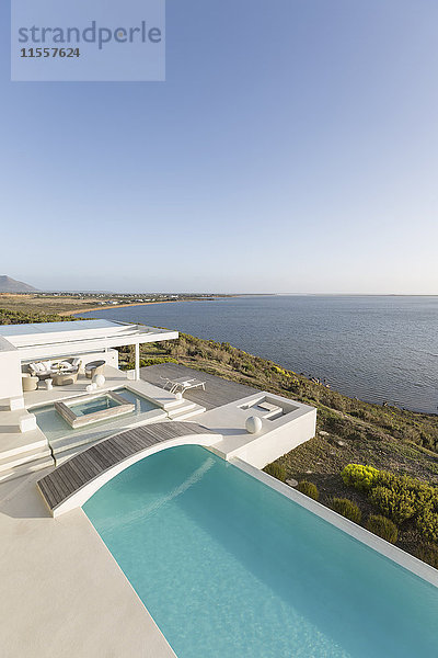 Sonniges  ruhiges  modernes Luxusdomizil mit Infinity-Pool und Steg und Meerblick unter blauem Himmel