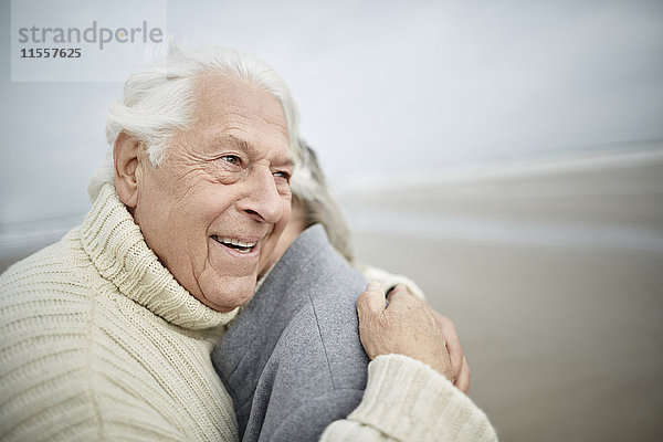Liebevolles Seniorenpaar beim Umarmen am Winterstrand