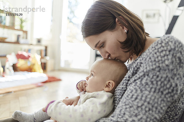 Mutter küsst kleine Tochter auf den Kopf