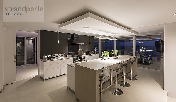 Beleuchtete moderne Luxuswohnung mit Vitrine in der Küche bei Nacht