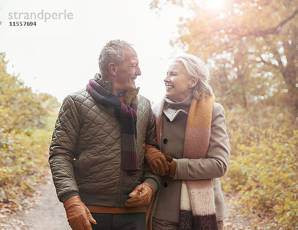 Liebevolles Seniorenpaar geht Arm in Arm auf Weg im Herbstpark