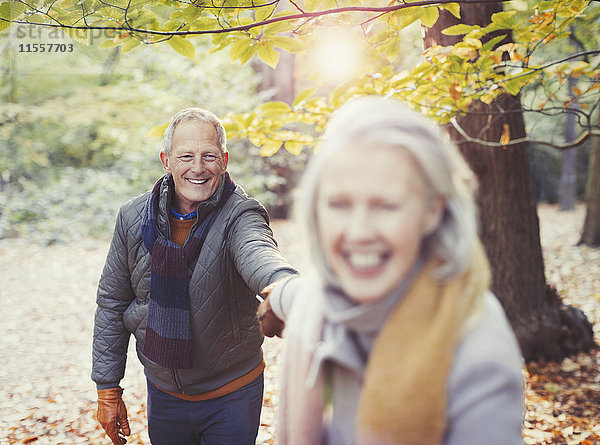 Verspieltes Seniorenpaar hält Händchen im Herbstpark